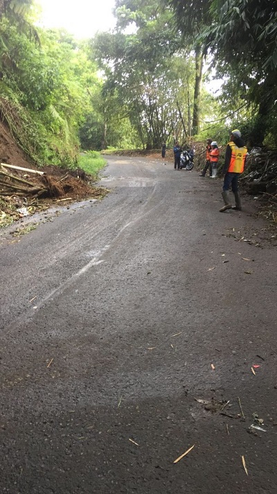 EVAKUASI: Petugas mengerahkan satu unit mobil pemadam kebakaran untuk menyemprotkan sisa material longsor yang masih menggantung di tebing.